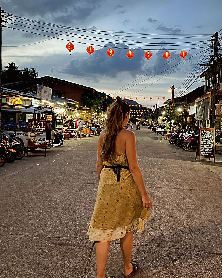Une femme de dos marche seule dans une rue au crépuscule
